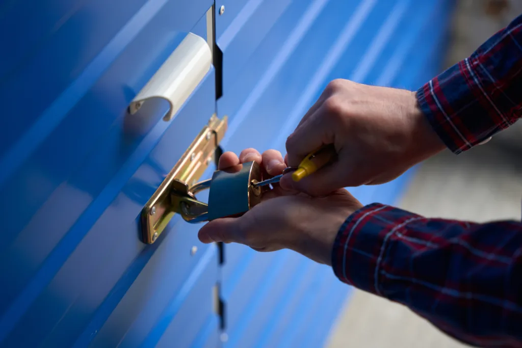 Man is opening the lock with key from self storage unit in warehouse